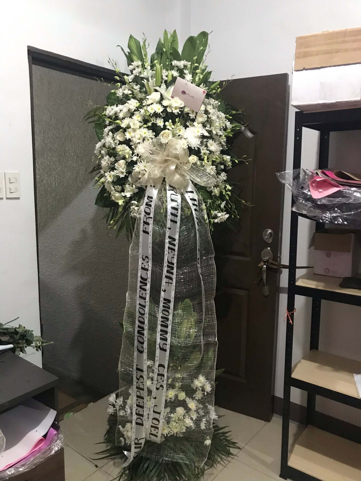 Infinity flower stand for peaceful condolences. Featuring Roses, Casa Blanca lilies, White Orchids, Spider Mums, and Radus flowers, this elegant arrangement in an infinity shape expresses everlasting love and sympathy.